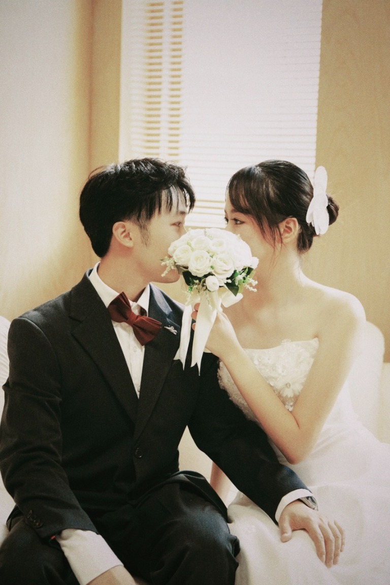 The couple smiling over a bouquet